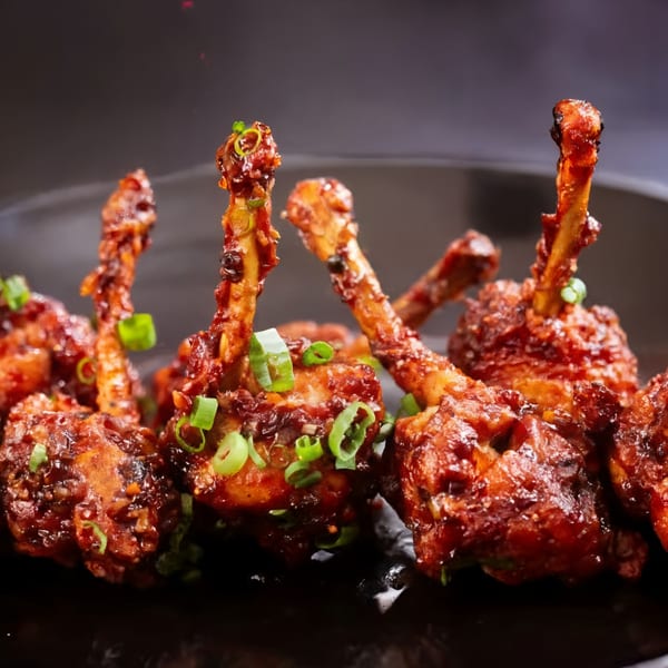Sweet Magic Indo-Chinese Restaurant's chicken lollipops, glazed and garnished with fresh green onions.