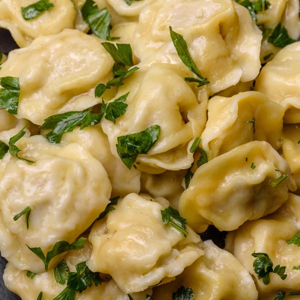 Close-up of Indian dumplings, possibly momos, garnished with fresh green herbs.