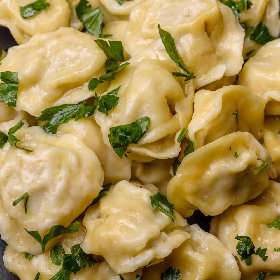Close-up of Indian dumplings, possibly momos, garnished with fresh green herbs.