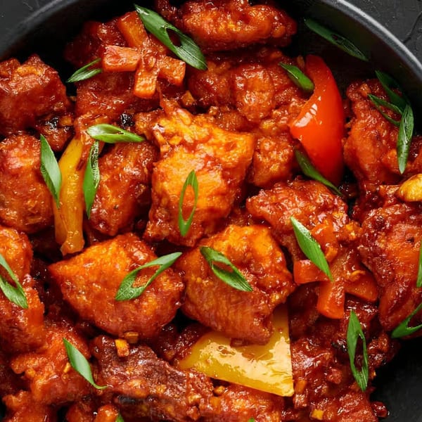 Sweet Magic Indo-Chinese Restaurant's chili chicken, garnished with green onions and bell peppers.